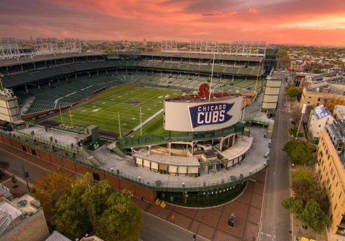 aerial shot of Wrigley Field with the Northwestern Wildcats football field on the grass of the stadium surrounded by autumn colored trees, streets and homes in Chicago Illinois USA