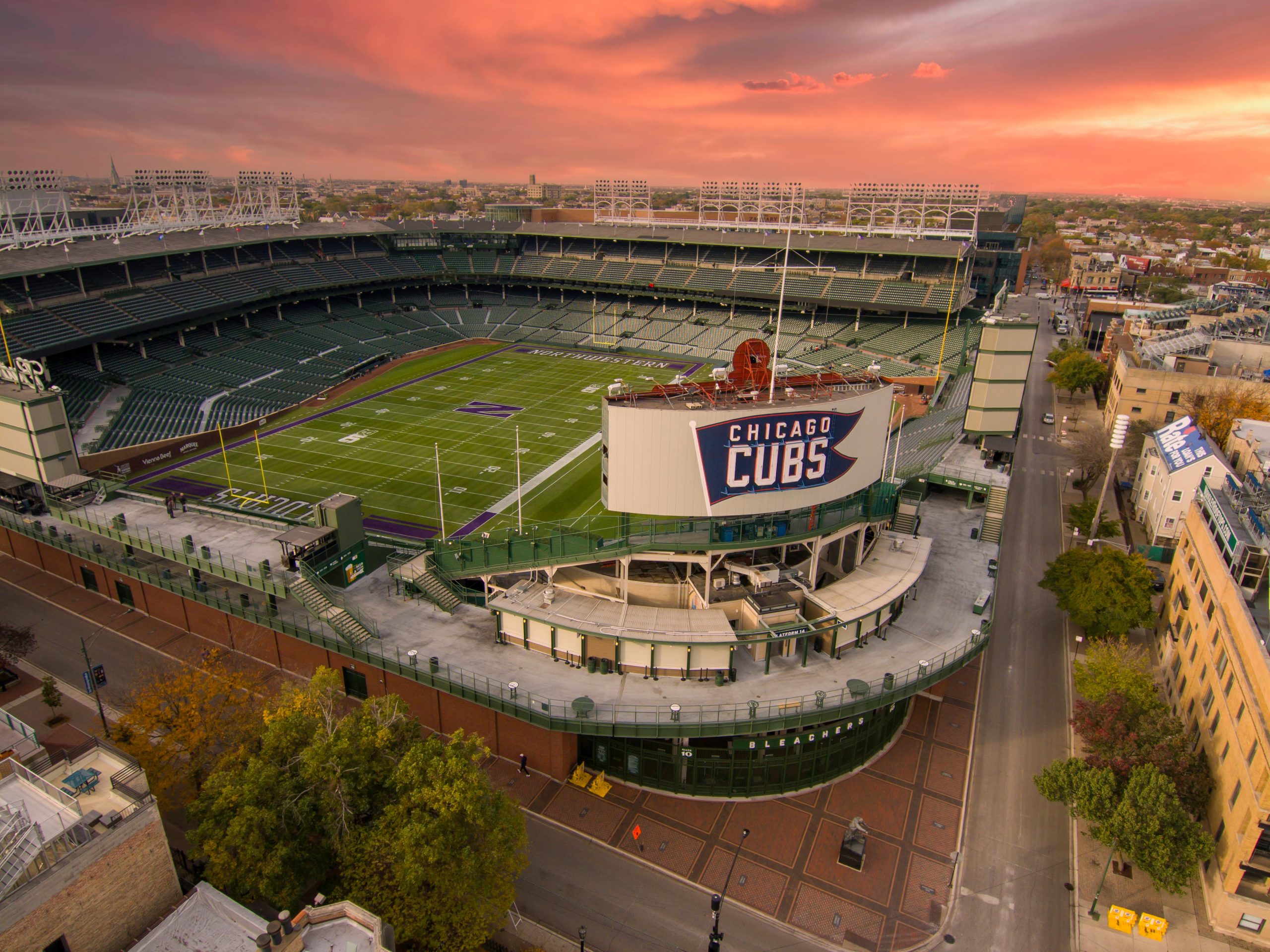 aerial shot of Wrigley Field with the Northwestern Wildcats football field on the grass of the stadium surrounded by autumn colored trees, streets and homes in Chicago Illinois USA